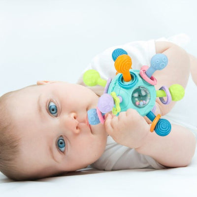 Hochet-bebe-turquoise-musical-dans la bouche d'un bébé à yeux vert