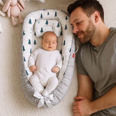 Réducteur de lit gris sapin de noël bébé endormi paisiblement à côté de papa