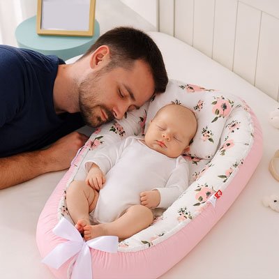 Reducteur de lit rose fleur bébé endormi à côté de papa sur un lit