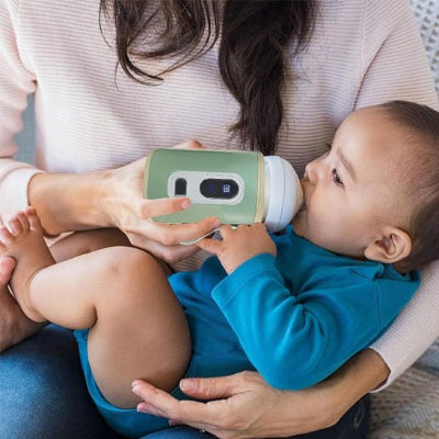 chauffe biberon attachable vert bébé habillé en bleu dans le bras de maman et prend son biberon