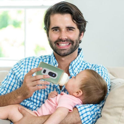 chauffe biberon attachable vert dans la bouche bébé dans le bars de papa souriant