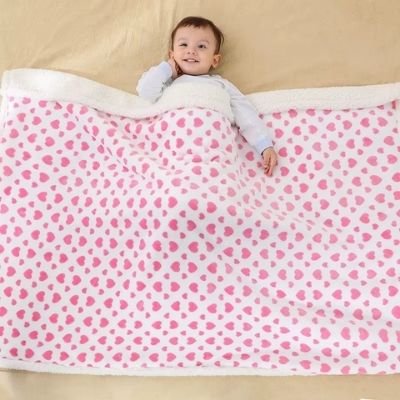 couette-bebe-motif-coeur-rose-couvrant-bébé-souriant-couché-mains-libres