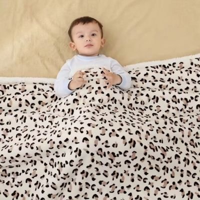 couette-bebe-blanche-motif-léopard-couvrant-bébé-couché-sur-lit-bras-libres