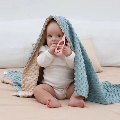 couverture-pour-bebe-bleu-beige-bébé-assis-sur-lit