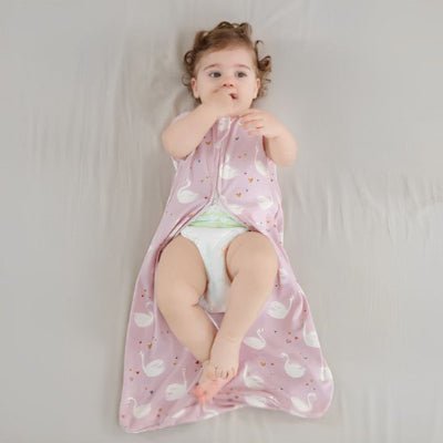 gigoteuse cygones rose ajustable bébé couché sur le lit les doigts dans la bouche