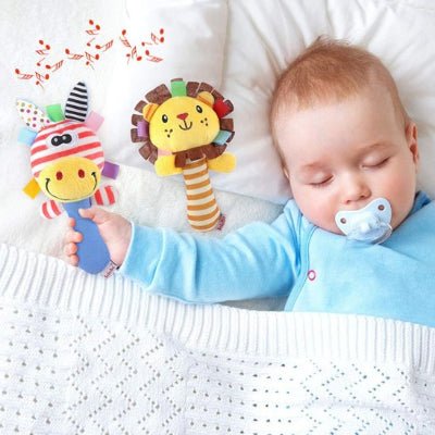 Hochet bébé musical lion jaune et âne rayé dans la main d'un bébé endormi avec une sucette bleue dans la bouche
