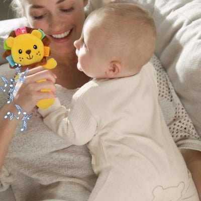 Hochet bébé musical lion jaune dans la main d'un bébé et maman souriante