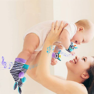 hochet bébé avec rayure porté par bébé souriant dans les mains de sa maman souriante