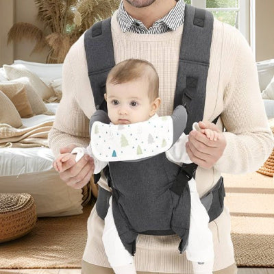papa porte son bébé en avant dans un porte bébé gris avec larges sangles sur l'épaule