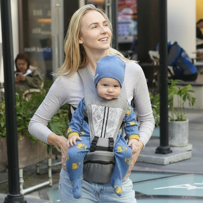 porte bébé gris maman souriante porte bébé habillé en bleu devant un restaurent 