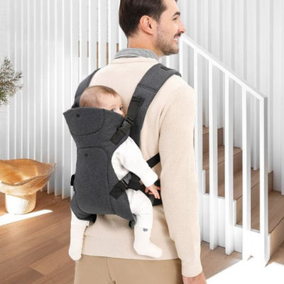 papa devant escalier blanc porte son bébé sur le dos dans un porte bébé noir