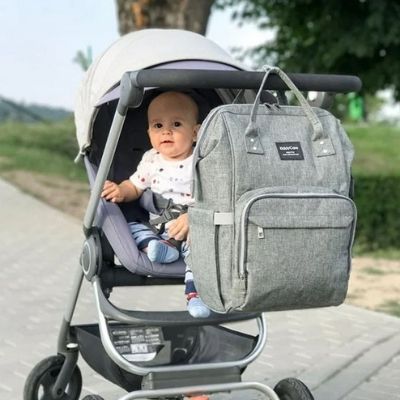 Sac-à-dos-à-langer-bebe-souriant-dans-poussette-grise